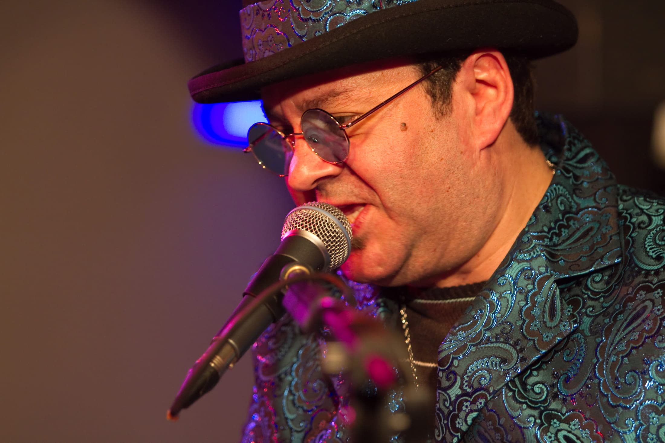 The performer leaning into the microphone mid-performance under magenta stage light